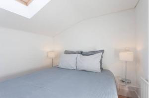 Casas São Julião في لشبونة: غرفة نوم بيضاء مع سرير مع مصباحين