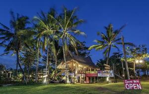 a resort with palm trees and a building with a sign at Keramas Surf Camp in Keramas
