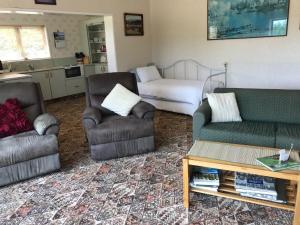 a living room with two couches and a kitchen at Llanerchymedd in Taihape