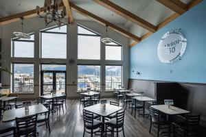a dining room with tables and chairs and large windows at Harbor 360 Hotel Seward in Seward