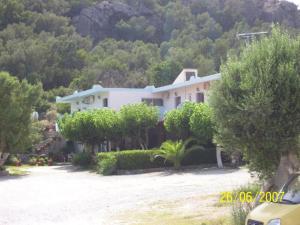 a large white house with trees in front of it at Nikos & Anna Rooms in Rodakino