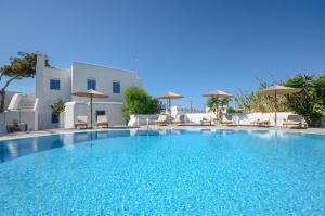 a large swimming pool with chairs and umbrellas at Naxian Queen Luxury Villas & Suites in Agia Anna Naxos