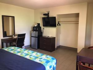 a hotel room with a bed and a desk and a television at American Inn Punta Gorda in Punta Gorda