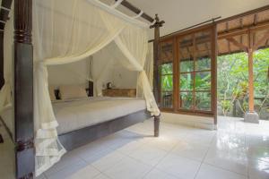 a bedroom with a bed with a canopy at Yuliati House in Ubud