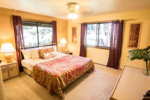 a bedroom with a bed and two windows at Hale Mauna Loa Upper Level with shared Hot Tub in Volcano