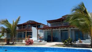 a house with a swimming pool and palm trees at Bella Vista condominio in Canoas de Punta Sal