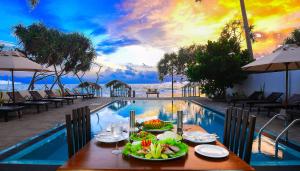 una mesa con platos de comida junto a una piscina en At Ease Beach Hotel, en Hikkaduwa