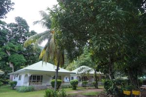 une maison blanche avec un palmier en face dans l'établissement Chalet Bamboo Vert, à La Digue