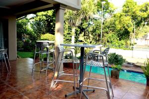 un patio con mesa, sillas y piscina en The Bedford View Guest House en Germiston