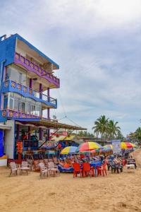 a building on the beach with chairs and umbrellas at Hotel Dolphin Hikkaduwa in Hikkaduwa