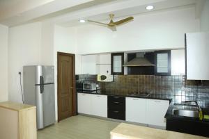 a kitchen with white cabinets and a ceiling fan at Swan Suites Madhapur in Hyderabad