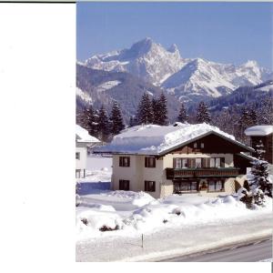 a house in the snow with a mountain in the background at Ferienwohnungen Passrugger in Eben im Pongau