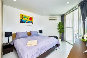 a bedroom with a bed with a purple bedspread at LUXURIOUS APARTMENT on JOMTIEN BEACH ROAD in Jomtien Beach