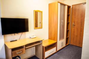 a room with a desk with a television and a cabinet at Kaštieľ Fričovce in Fričovce