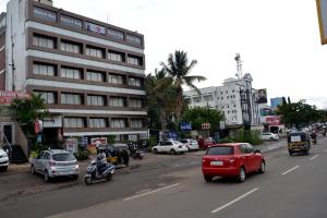 una trafficata strada cittadina con auto e moto e un edificio di Hotel Raj ad Aurangabad