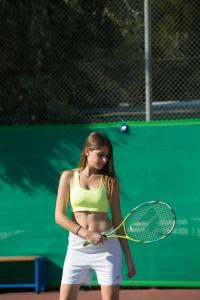 a woman holding a tennis racket on a court at Porto Galini Seaside Resort & Spa in Nikiana
