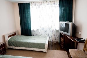 a bedroom with a bed and a tv and a window at Belovezhskaya pushcha Hotel №2 in Kamenyuky