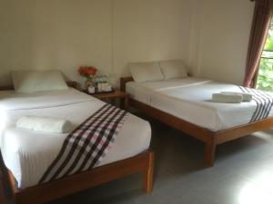 two twin beds in a room with a window at paibaansuan in Pai