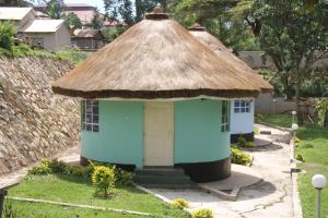 a small hut with a thatched roof in a yard at Sheywe Hotel Kakamega in Kakamega
