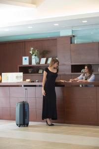 a woman standing in front of a counter with a suitcase at Porto Galini Seaside Resort & Spa in Nikiana