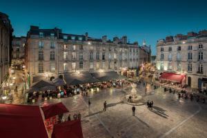 Un groupe de personnes se promenant autour d'une place de la ville la nuit dans l'établissement Villa Reale, à Bordeaux