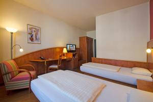 a hotel room with two beds and a desk at 1, 2, sleep Boardinghouse Unterschleißheim Zentrum in Unterschleißheim