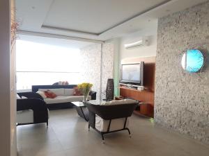 a living room with a couch and a tv at Amplio- Espectacular 140m2 Grand Diamond Tonsupa in Tonsupa