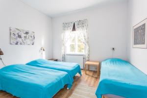 2 camas en una habitación blanca con sábanas azules en Brukshotellet Roma B&B, en Romakloster