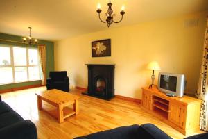 a living room with a fireplace and a tv at Doonbeg Holiday Homes in Doonbeg