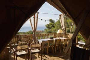 una mesa y sillas en una terraza con vistas al océano en Tente Lodge Bord de Mer en Coti-Chiavari