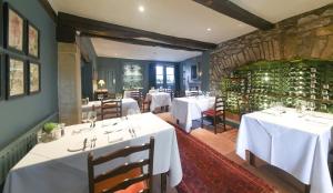 a restaurant with white tables and chairs and a stone wall at The Traddock in Austwick