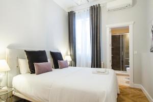 1 dormitorio con 1 cama blanca grande con almohadas rosas en Minty Stay - Atocha 4 BD en Madrid