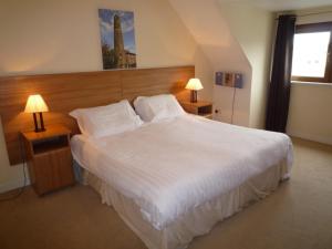 バリーコットンにあるシャナガリー ホリデイ ヴィレッジのベッドルーム(白い大型ベッド、ランプ2つ付)