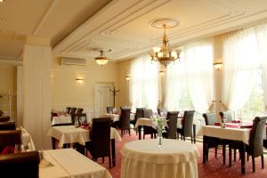 ein Restaurant mit Tischen, Stühlen und einem Kronleuchter in der Unterkunft Luxury Garni Hotel Brix in Bratislava