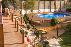 a person walking down a wooden deck next to a pool at Good Feeling Hostel & Guest House in Raposeira