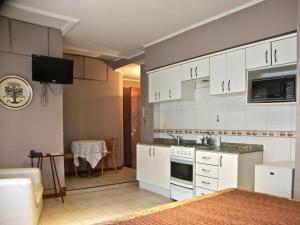 a kitchen with white cabinets and a sink and a table at Loft Argentino Apart Buenos Aires in Buenos Aires