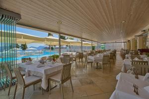 a restaurant with white tables and chairs and a pool at Porto Galini Seaside Resort & Spa in Nikiana