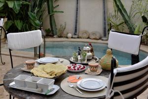 a table with food on it next to a swimming pool at Riad les Ammonites and Spa in Marrakesh
