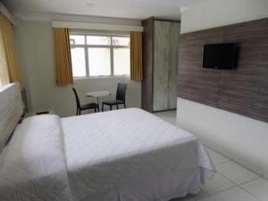 a bedroom with a bed and a table and a television at Hotel Rodrigues in Garanhuns