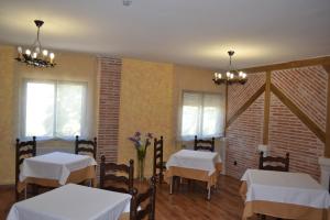 a dining room with two tables and chairs and two windows at La Posada de Rosa in Hita