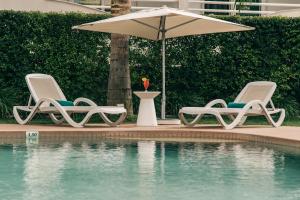two chairs and an umbrella next to a swimming pool at Velamar Boutique Hotel - Adults Friendly in Albufeira