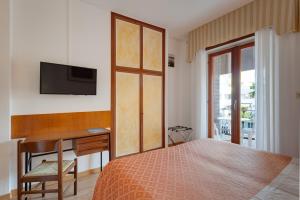 sypialnia z łóżkiem, biurkiem i telewizorem w obiekcie Hotel Helvetia w Grado