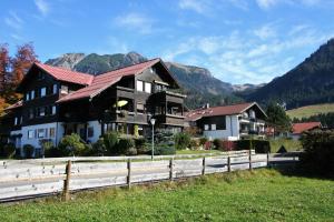 ein Haus mit einem Zaun und Bergen im Hintergrund in der Unterkunft Alpenflair Ferienwohnungen Whg 214 "Schanzenblick" in Oberstdorf + 13 Fotos