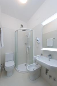 a bathroom with a shower and a toilet and a sink at Hotel Helvetia in Grado