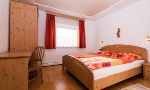 a bedroom with a bed and a desk and a window at Pramulin in Selva di Val Gardena