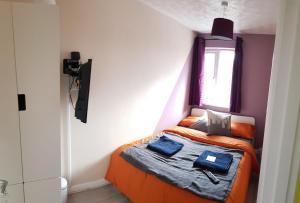 a small bedroom with an orange bed with a window at Columbine, Thetford, 2BR House in Thetford