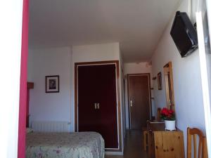 1 dormitorio con 1 cama y TV en la pared en Hostal Magnolia en Lloret de Mar