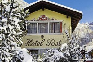 un cartel de hotel en la nieve frente a un edificio en Hotel Post en Großkirchheim