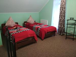 two beds with red covers in a room at Oselya Guest House in Yahotyn