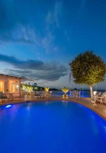 uma grande piscina azul com cadeiras e uma árvore em Oasis Beach Hotel em Skala